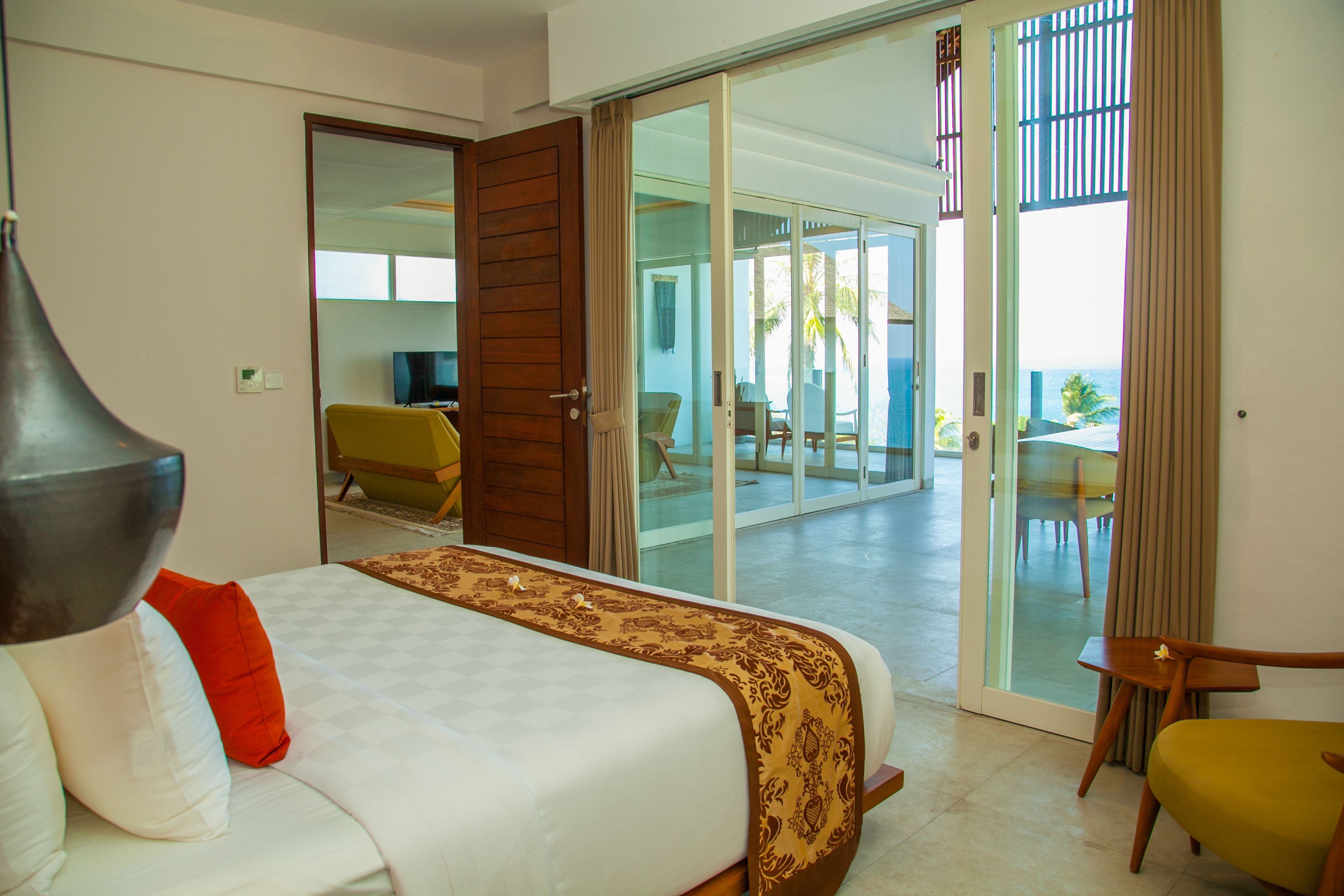 A hotel room with a bed, a chair, and a view of the outside.
