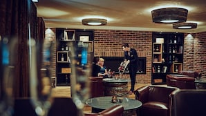 A cozy lounge area with leather seating, a brick wall, and shelves with bottles. - Die Burg (Donaueschingen)