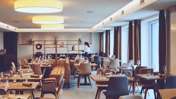 A spacious hotel dining area with multiple tables and chairs, a central seating area, and large windows allowing natural light. - Die Burg (Donaueschingen)