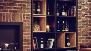 A brick wall with a wooden bookshelf containing various items including books, bottles, and decorative objects. - Die Burg (Donaueschingen)