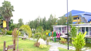 A garden with a pathway, benches, and a building with a blue roof. - Phalagoon Natural Resort @ Rayong (Ban Chang)