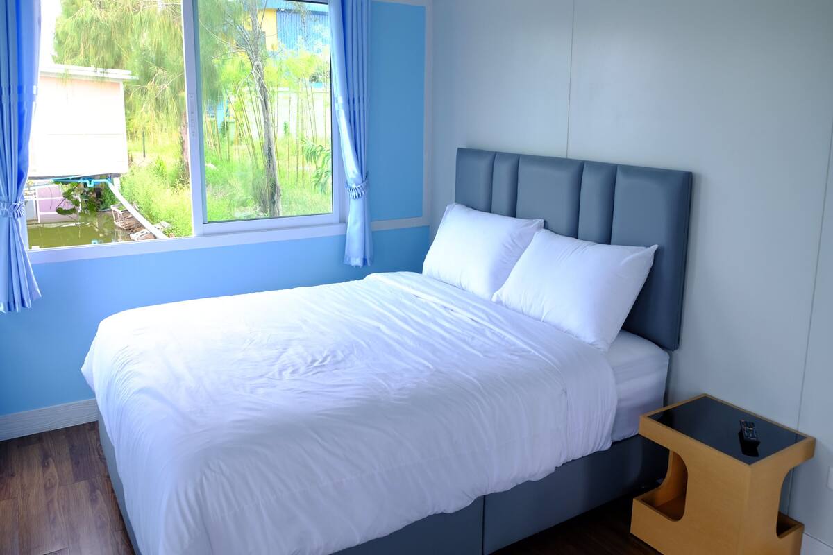 Une chambre à coucher avec un lit, une table de chevet et une fenêtre avec des rideaux.