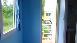 A room with a view of a wooden deck and a yellow building outside. - Phalagoon Natural Resort @ Rayong (Ban Chang)