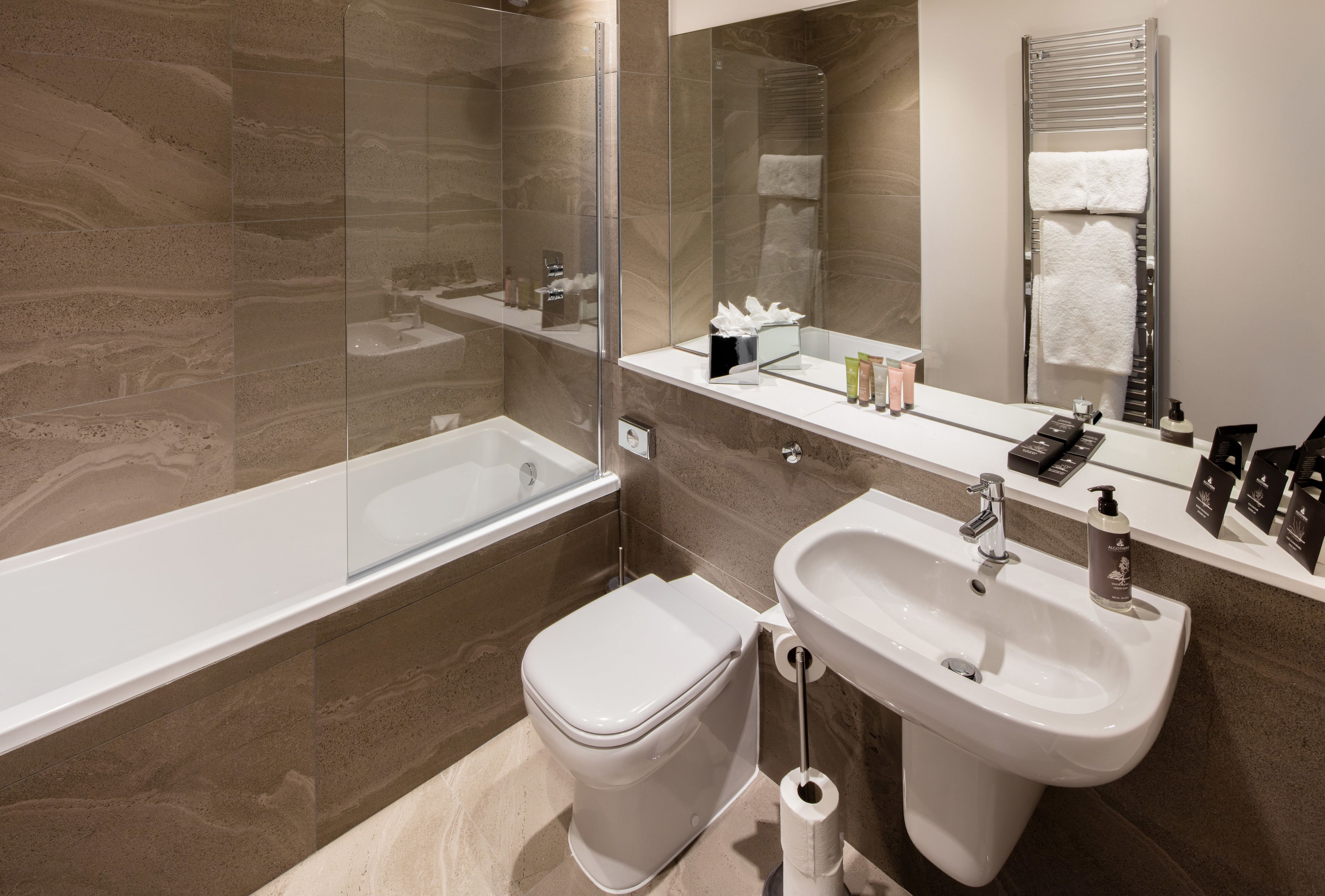 Une salle de bain moderne avec une douche à parois de verre, des toilettes blanches, un lavabo avec un miroir et un porte-serviettes.