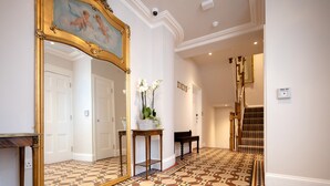 A hallway with a patterned floor, a large mirror, a staircase, and a door. - Beech House (Bristol)