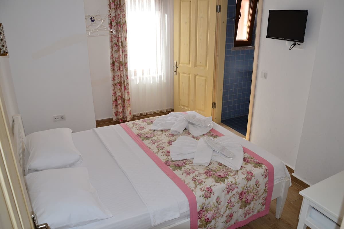 A hotel room with a bed, a television mounted on the wall, and a door leading to another room.