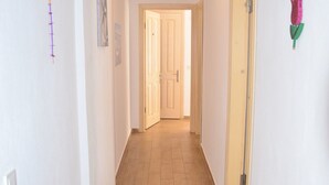 A narrow hallway with wooden flooring, white walls, and a door at the end. - Mercanay Butik Otel (Ayvalik)