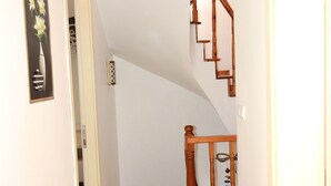 A hallway with wooden flooring, a wooden staircase, and a hanging light fixture. - Mercanay Butik Otel (Ayvalik)