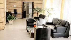 Un moderno vestíbulo de hotel con mostrador de recepción, zona de estar y plantas en macetas.