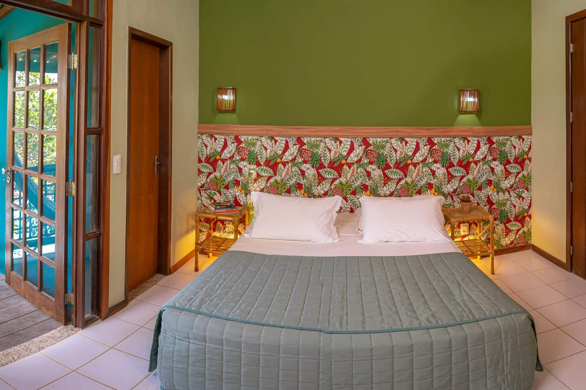Een slaapkamer met een bed, twee nachtkastjes, een groene wand en een deur.