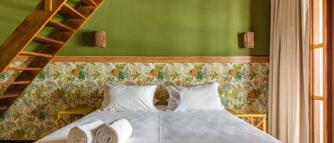 A bedroom with a wooden ladder, a bed with white linens, and a floral-patterned wallpaper.