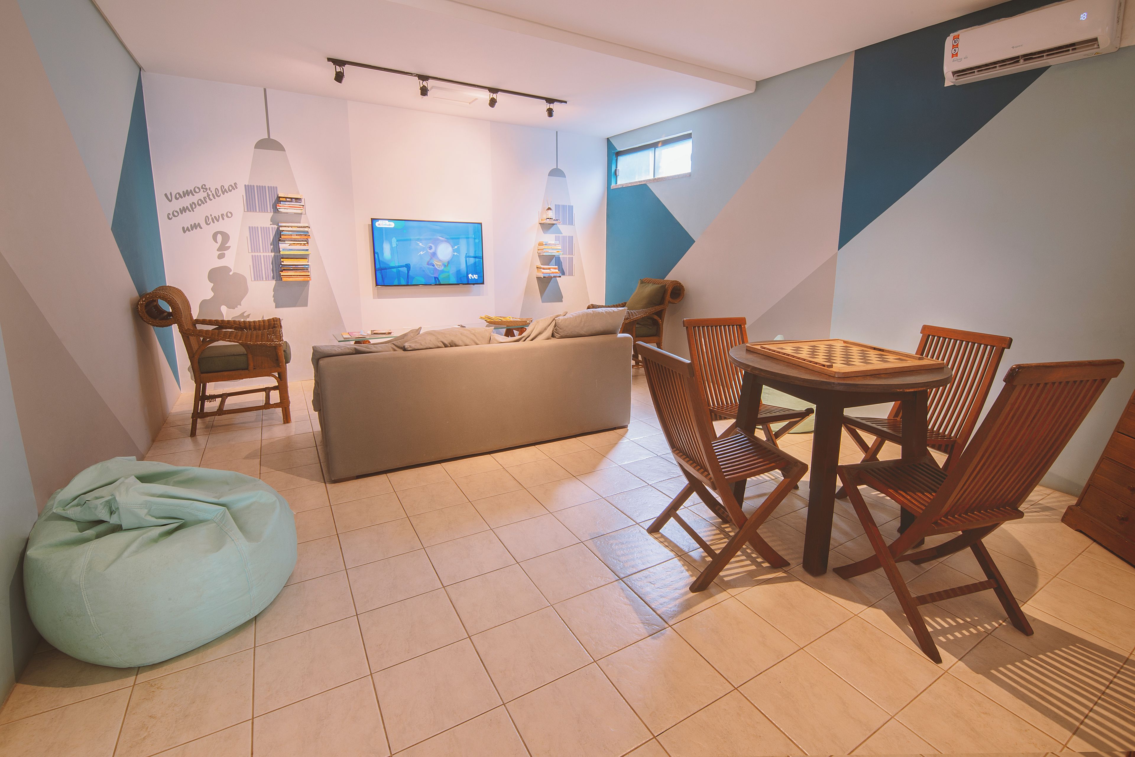 Una sala de estar moderna con un sofá, una mesa de comedor con sillas, un sillón informal y un televisor montado en la pared.