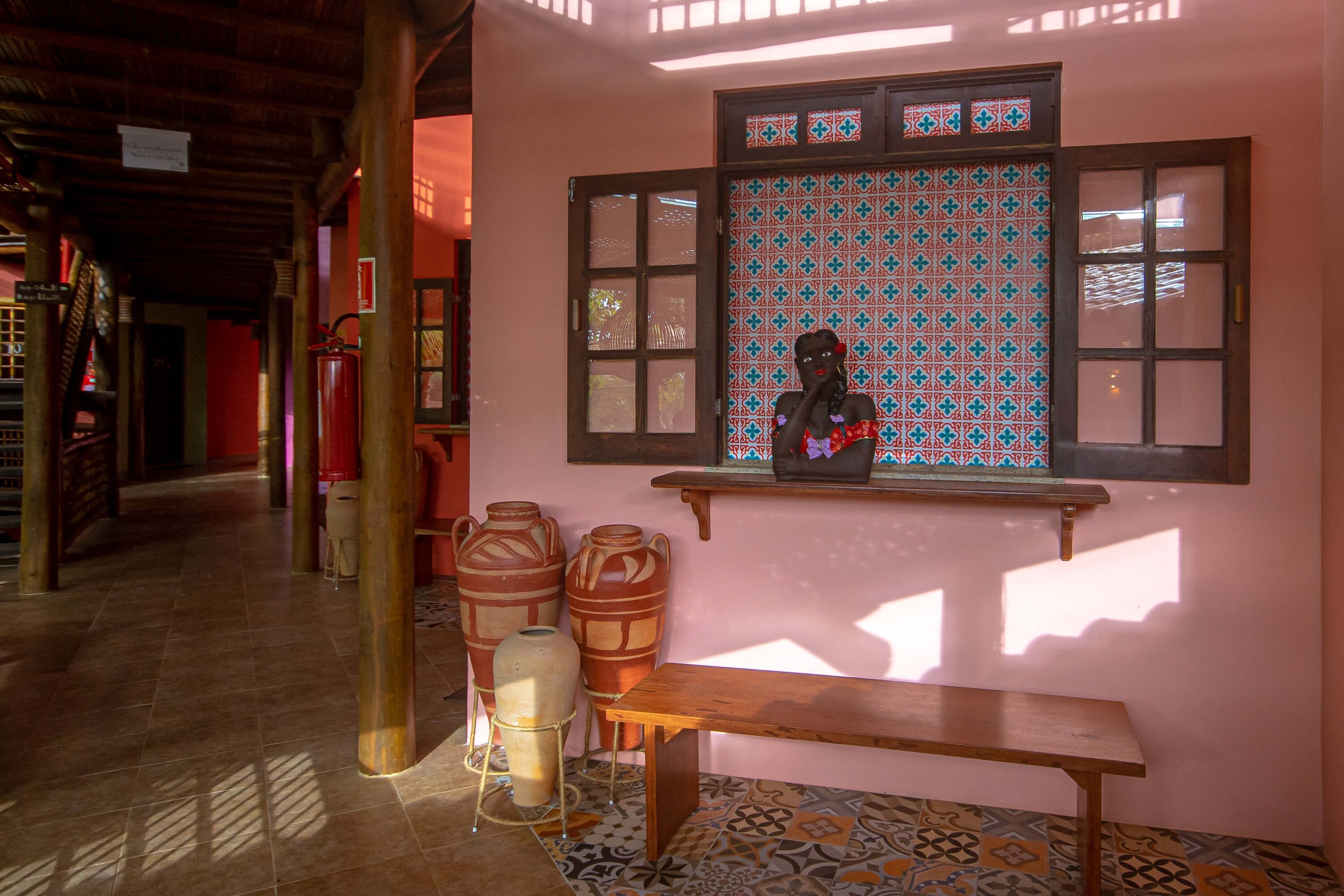 A corridor with a wooden bench, large pottery vases, and a window with patterned glass.