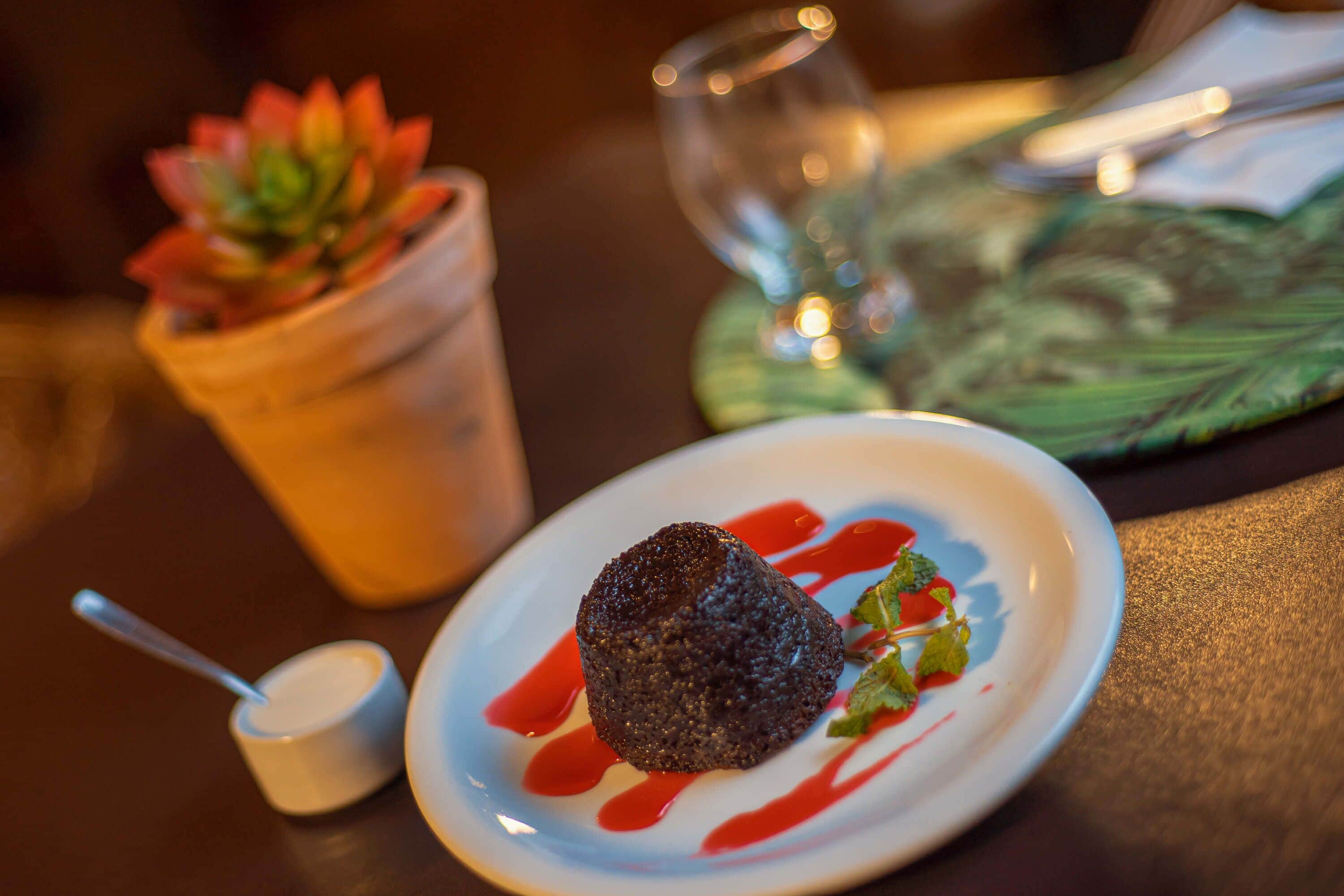 A dessert on a plate with a spoon and a small cup beside it.
