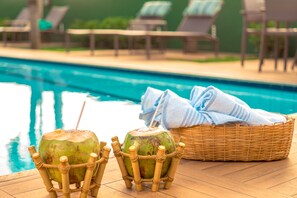 A poolside area with two coconuts in bamboo holders and a wicker basket with towels. - Pousada Villa Maeva Itacimirim (Camaçari)