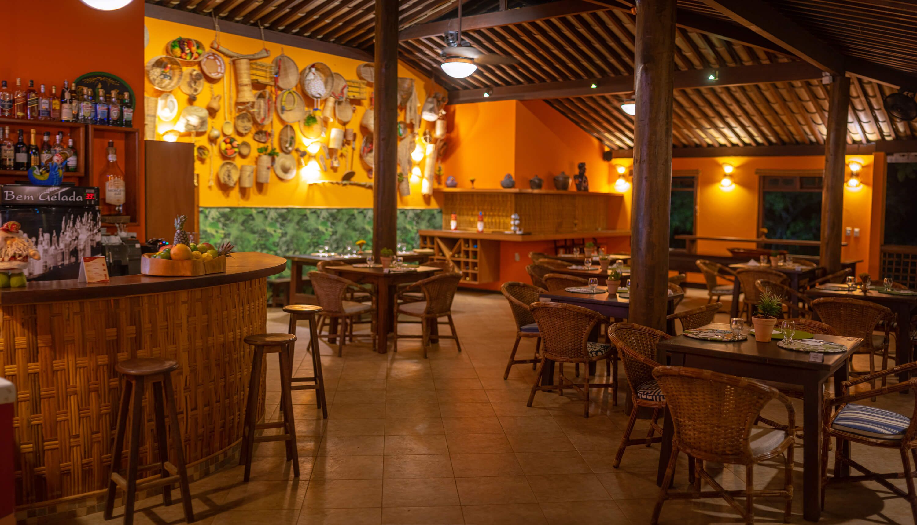 Ein Restaurant mit Barbereich, Korbmöbeln und einer Wand, die mit verschiedenen Gegenständen dekoriert ist.