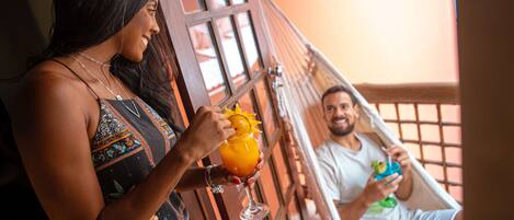 A person holding a drink in a hammock, with another person in the background.