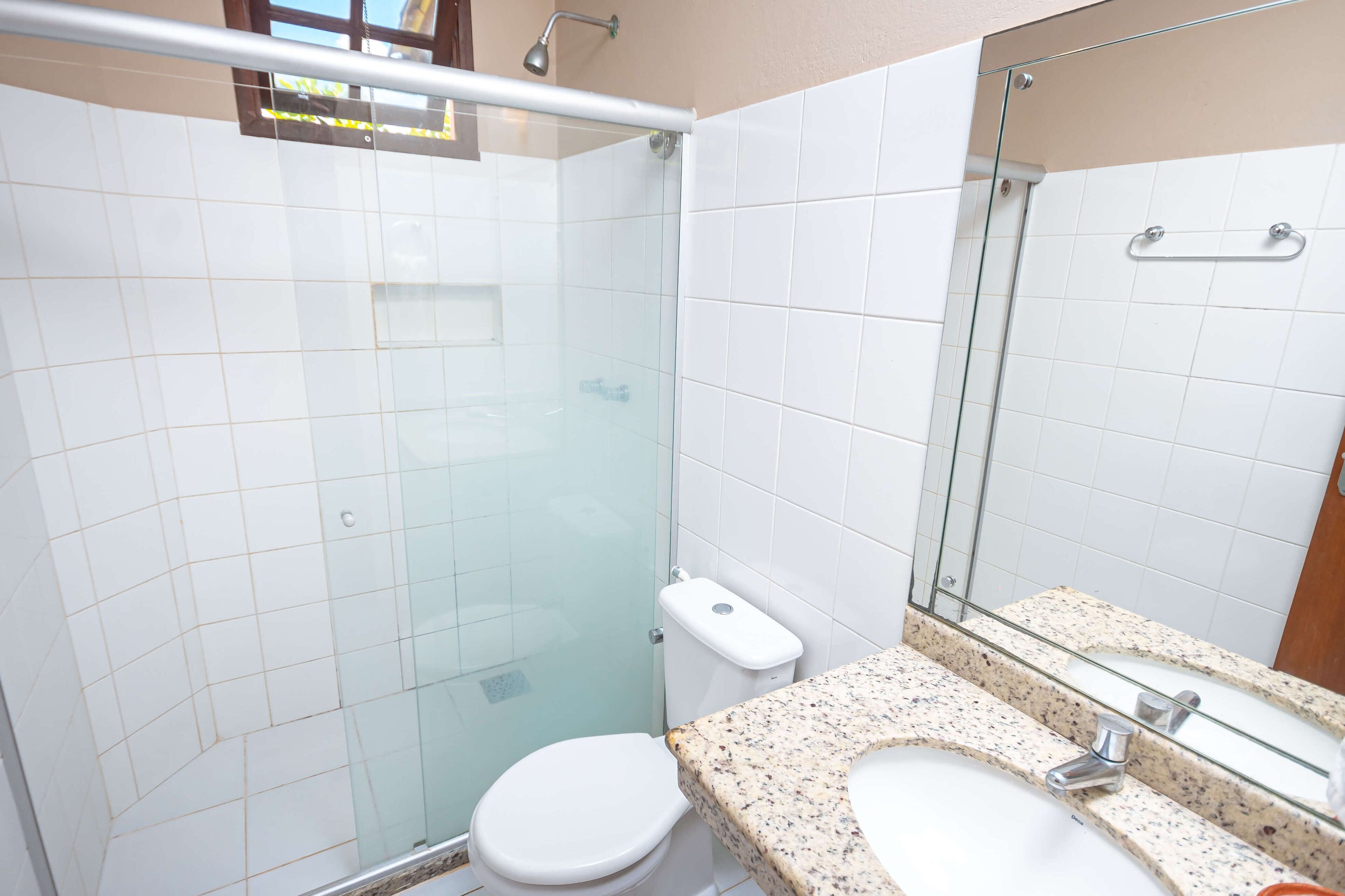 Ein Badezimmer mit Duschkabine, Toilette und Waschbecken mit Granitplatte.