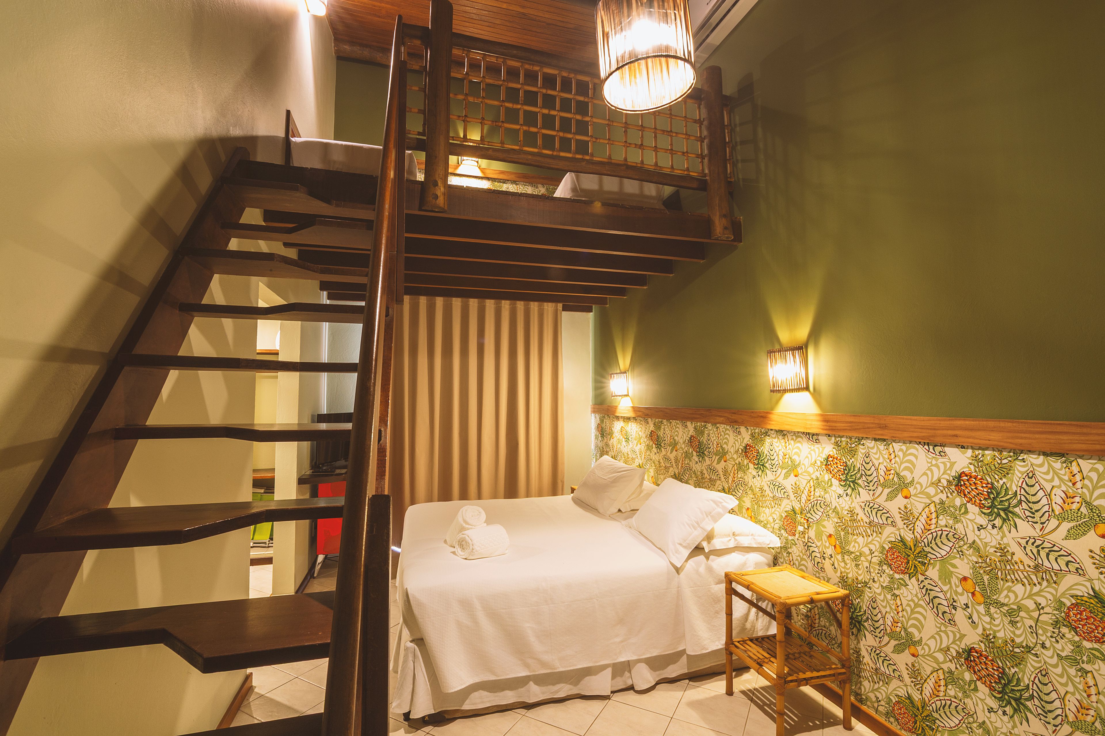 Un dormitorio con una cama, una mesita, una escalera de madera y una pared con estampado floral.
