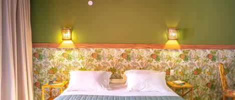 Una habitación con cama, dos mesitas de noche, una silla y papel tapiz con motivos florales.