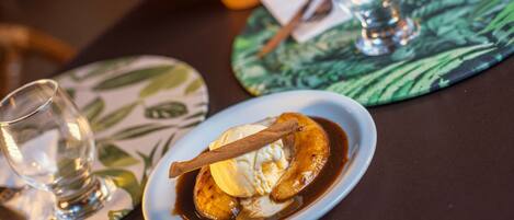 Prato de sobremesa com banana, sorvete e um pau de canela sobre uma mesa com um jogo americano.