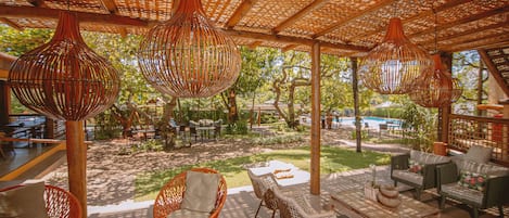 An outdoor seating area with wicker furniture and hanging light fixtures.