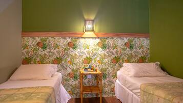 A room with two beds, a wooden nightstand, and a wall with a fruit pattern.