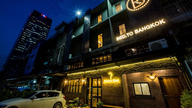 A hotel with a prominent 'B' logo, a sign reading 'BED TO BANGKOK', and a car parked in front. - Bed To Bangkok - Hostel (Bangkok)
