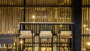 A bar area with bamboo partitions, wooden chairs, and a bar counter. - Bed To Bangkok - Hostel (Bangkok)