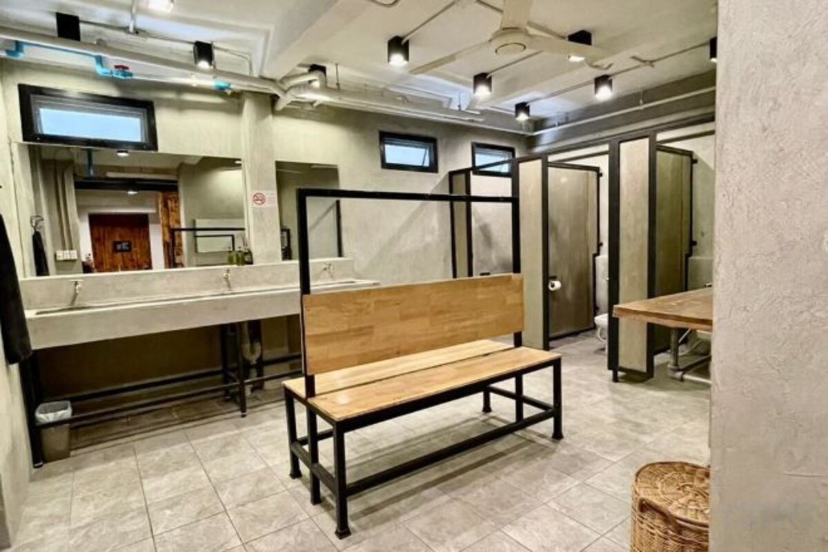 Des toilettes avec un banc en bois, des miroirs et un sol carrelé.