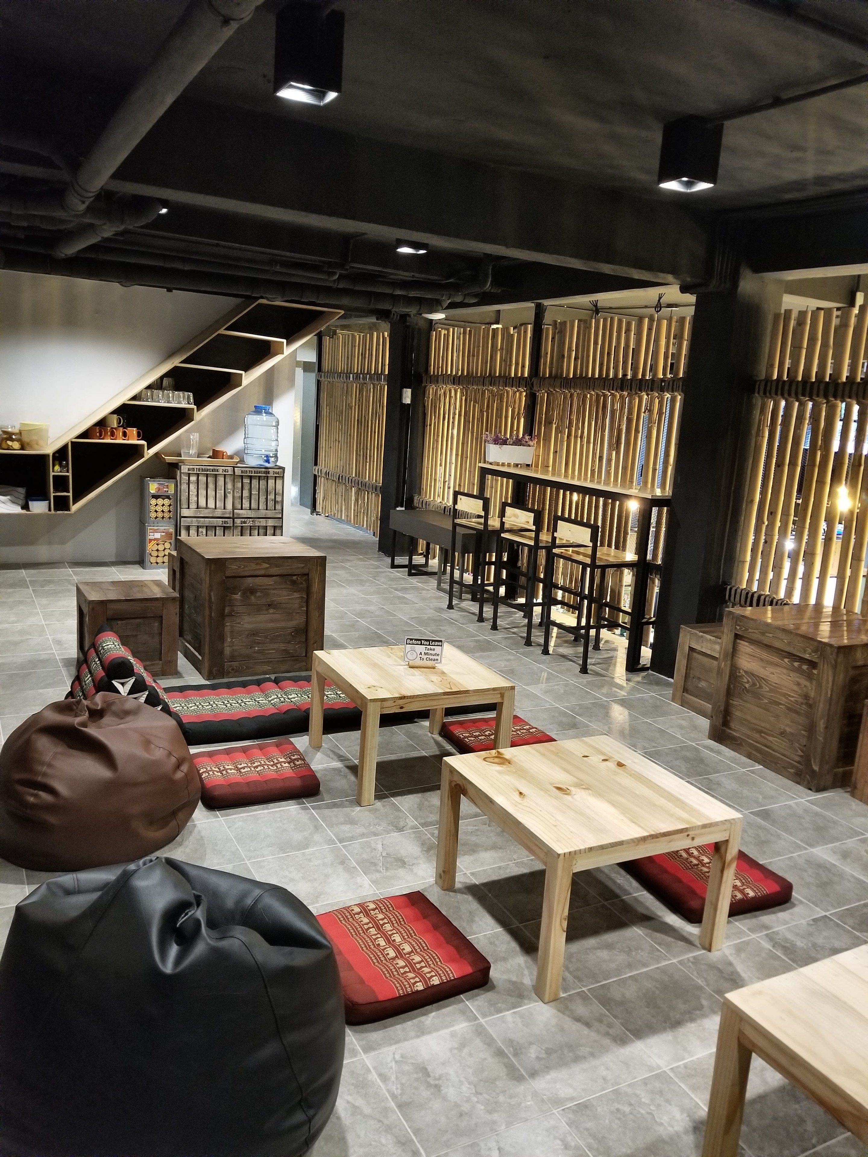 A modern interior with wooden tables and benches, a staircase, and bamboo partitions.