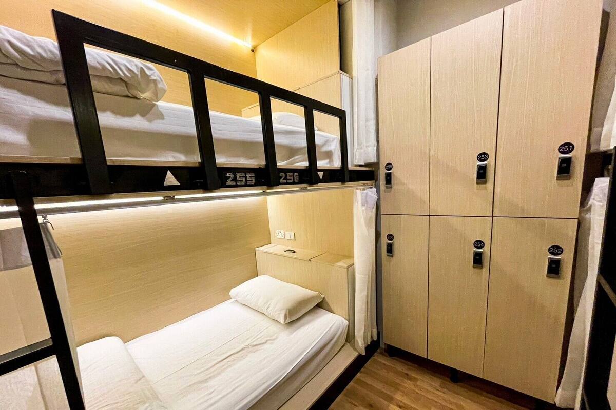 A compact hotel room with a bunk bed, wooden cabinets, and a small bedside table.