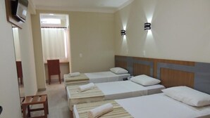 A hotel room with four single beds, a wooden bench, a TV, and a window with curtains. - Pérola Verde Hotel (Birigui)