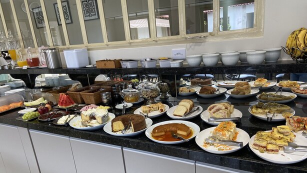 A buffet with various dishes including cakes, fruits, and salads. - Pérola Verde Hotel (Birigui)