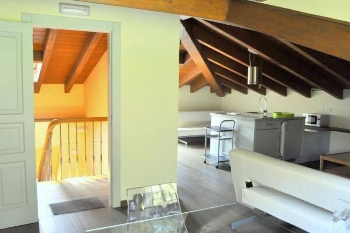 Une cuisine moderne avec un plafond en bois, un canapé blanc et une table en verre.