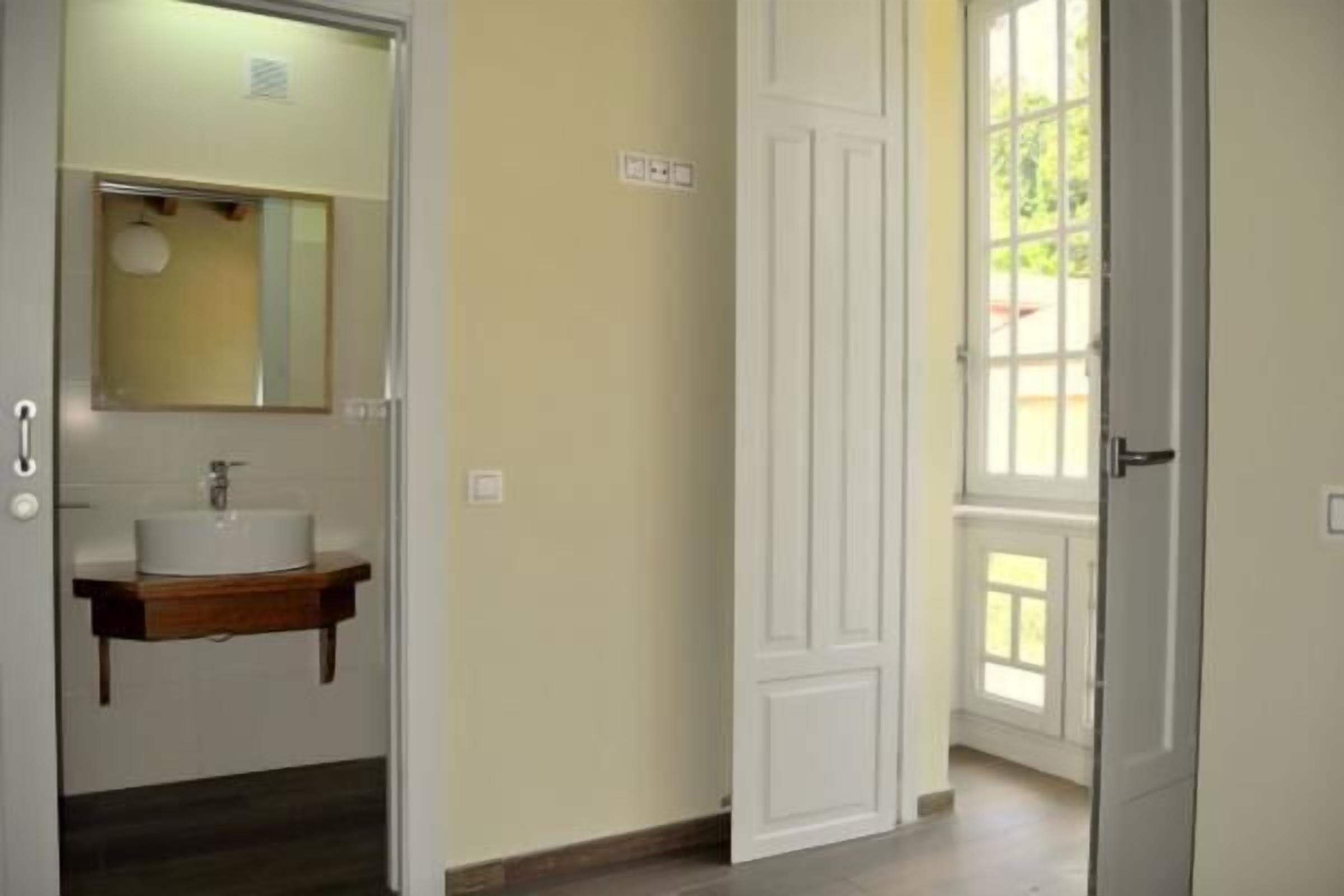 A bathroom with a white sink, mirror, and wooden vanity.