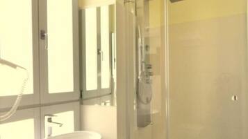 Ein Badezimmer mit Duschkabine aus Glas, Waschbecken und Spiegel.