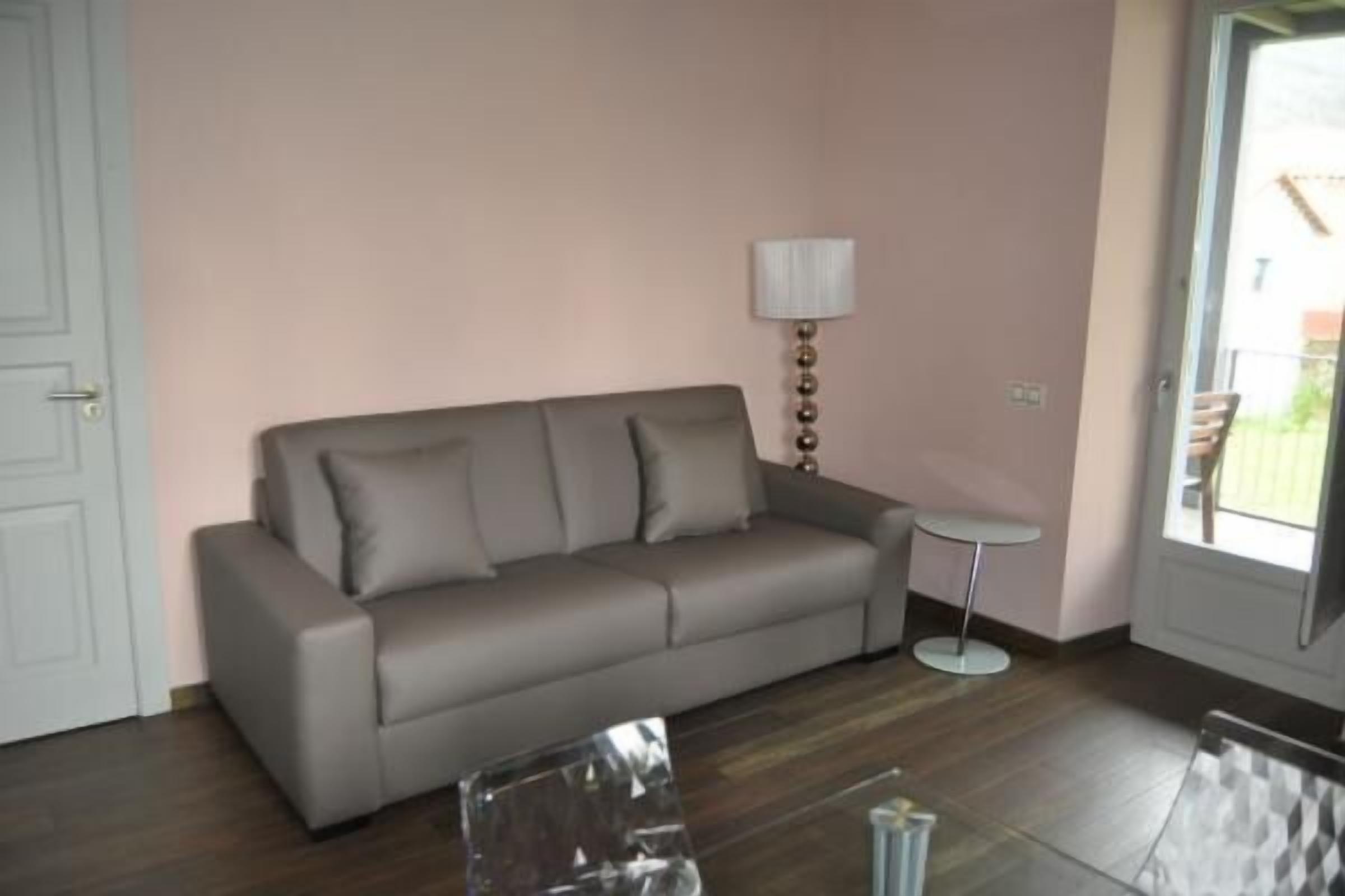 Un salon avec un canapé gris, une petite table ronde et une lampe.