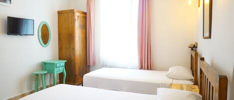 A room with two beds, a TV, a wooden wardrobe, and a small stool.