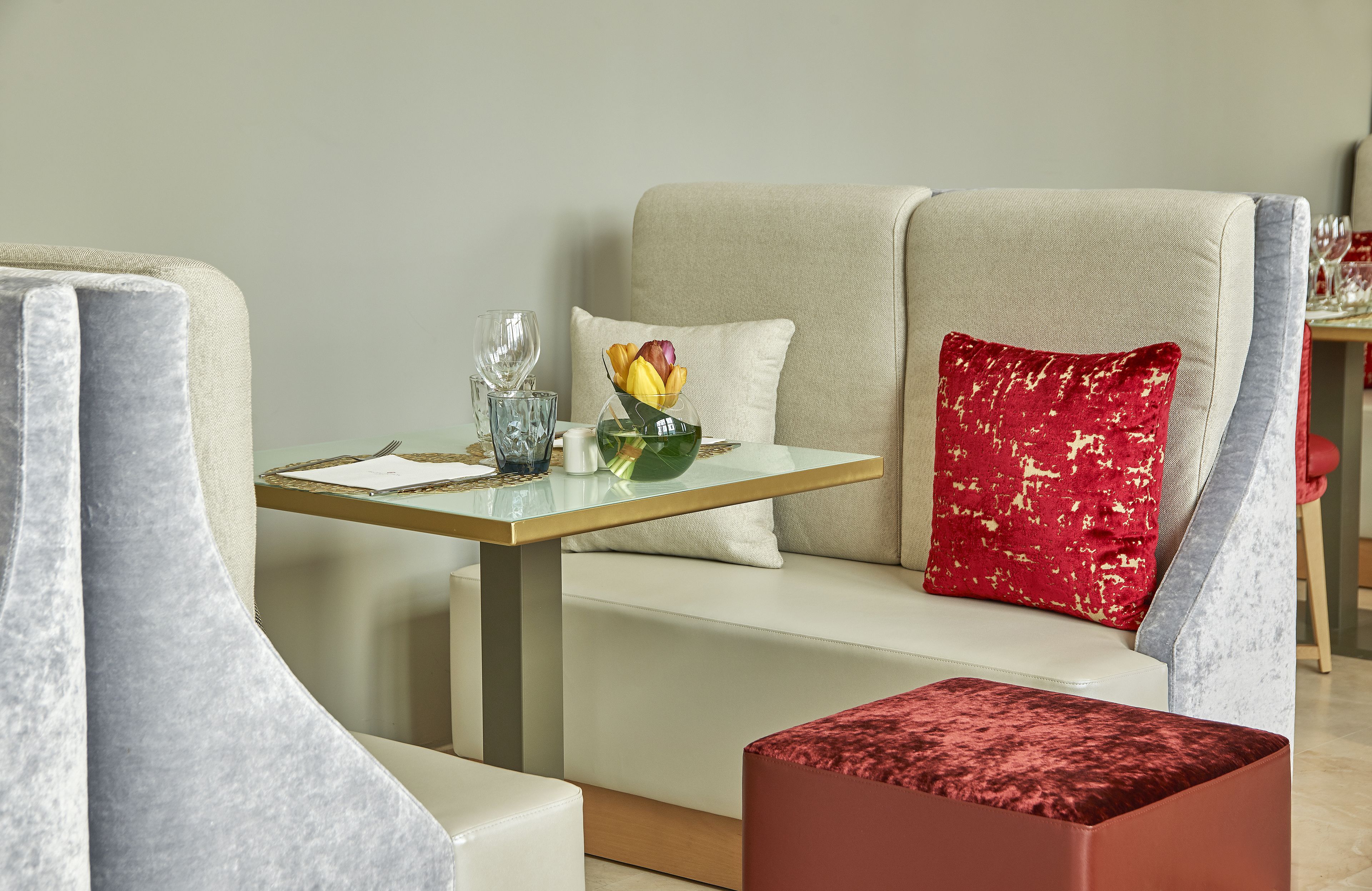 Un comedor moderno con una mesa de vidrio, asientos acolchados y un frutero decorativo.
