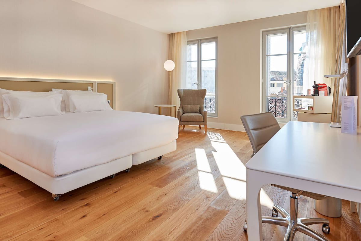 Une chambre d’hôtel avec un grand lit, un bureau, une chaise et une petite table.