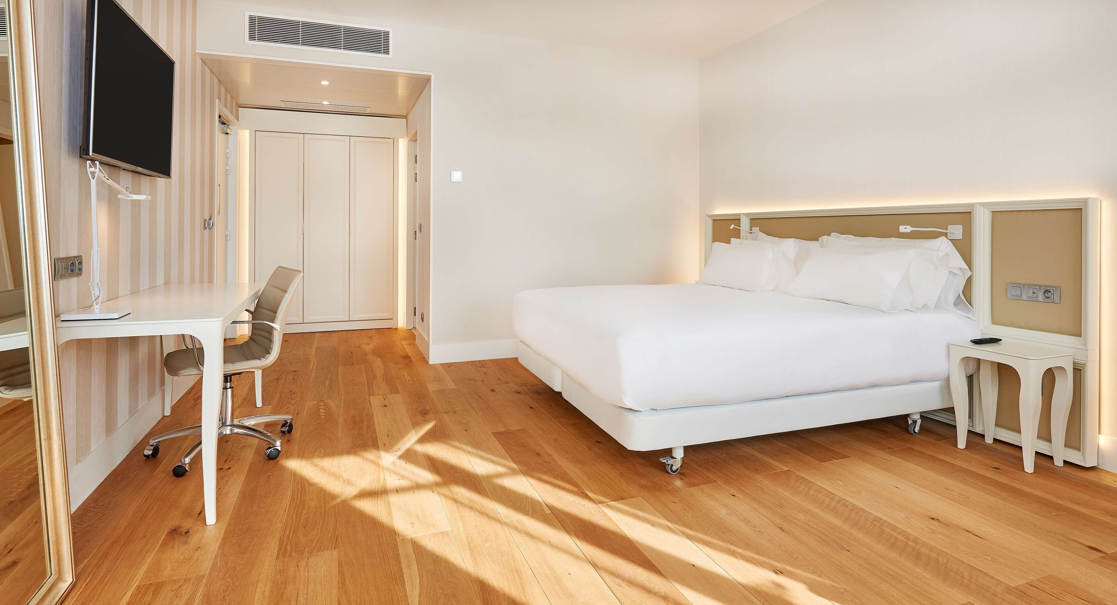A hotel room with a bed, a desk, a chair, and a TV.