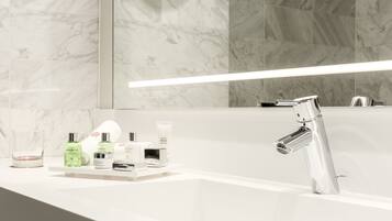 Une salle de bain moderne avec un pare-baignoire en marbre, un grand miroir et un robinet chromé.