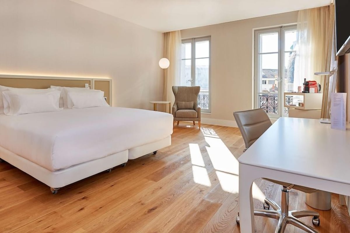 Una habitación de hotel con cama, una silla, un escritorio y una ventana.