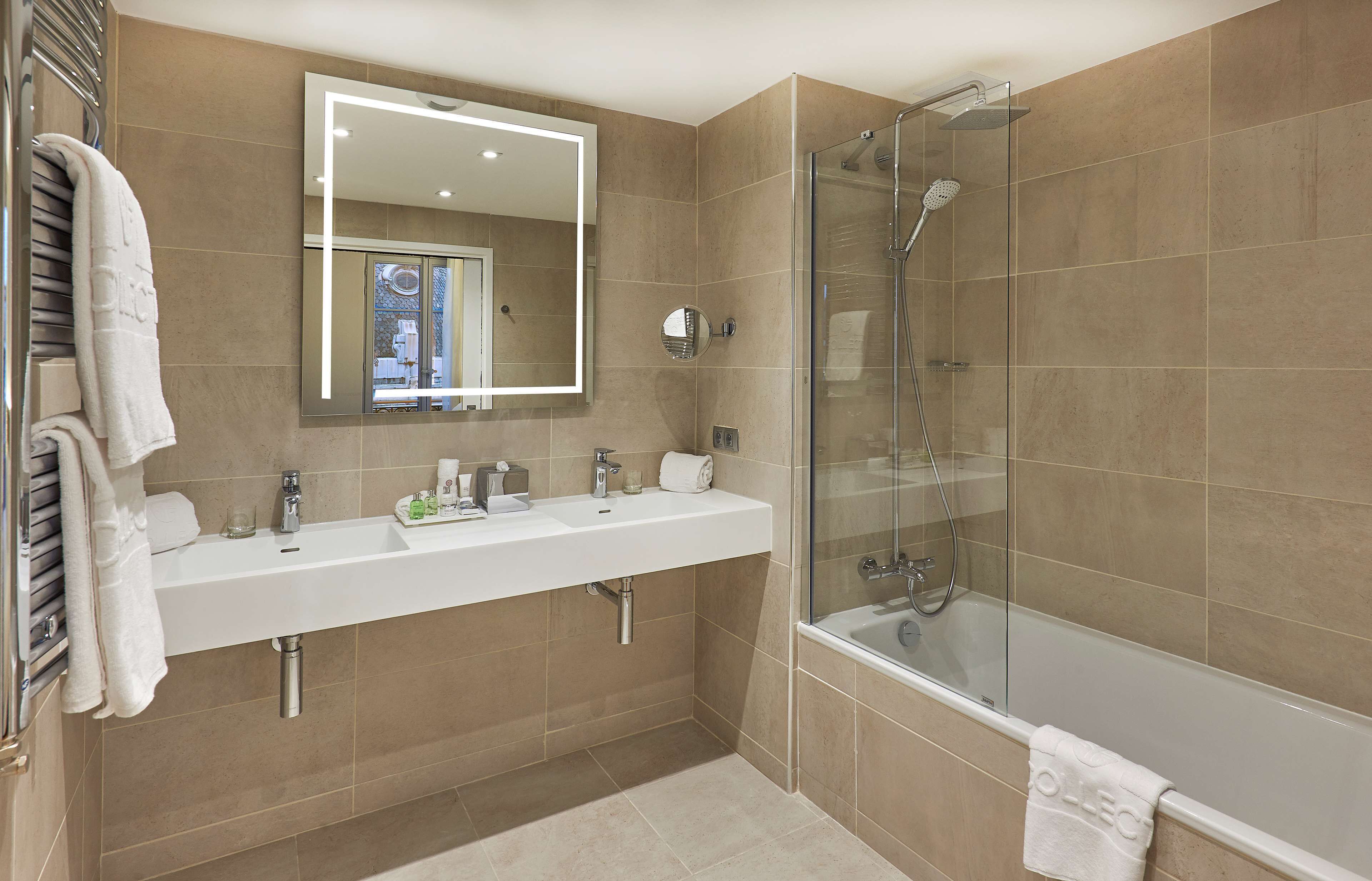A modern bathroom with a glass-enclosed shower, a large mirror, and a white vanity with a sink and countertop.