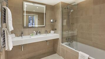 Un baño moderno con ducha de vidrio, un espejo grande y un tocador blanco con lavamanos y encimera.
