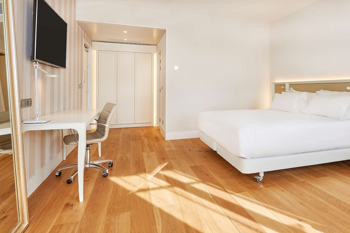Une chambre d’hôtel avec un lit, un bureau, une chaise et un téléviseur.