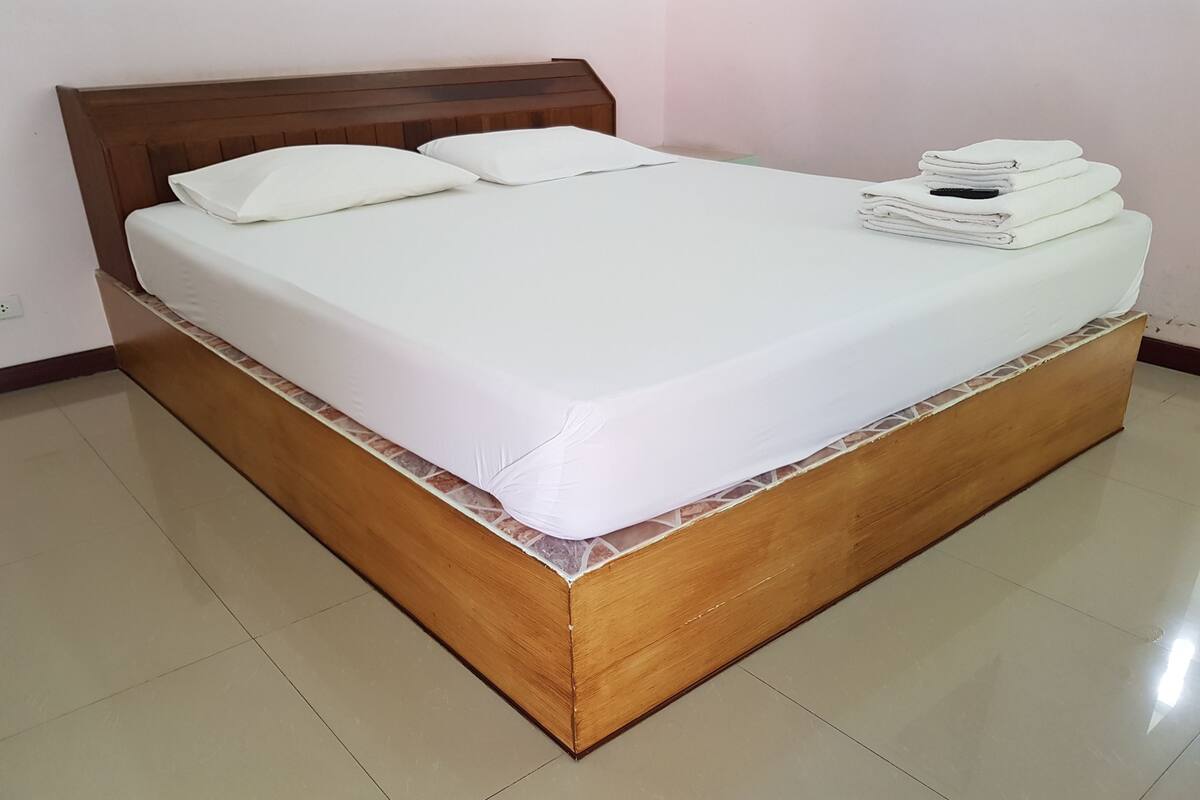 A neatly made bed with a wooden headboard and a white mattress.