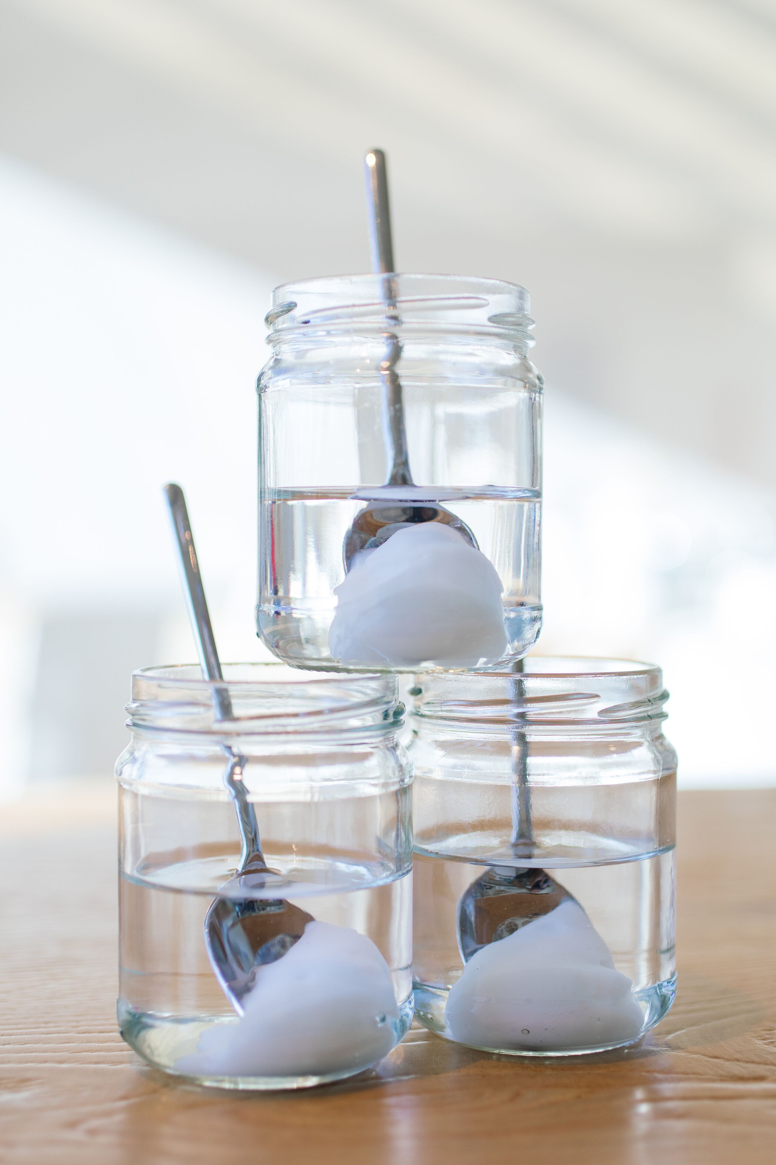 Three clear glass jars with spoons, each containing a white object.