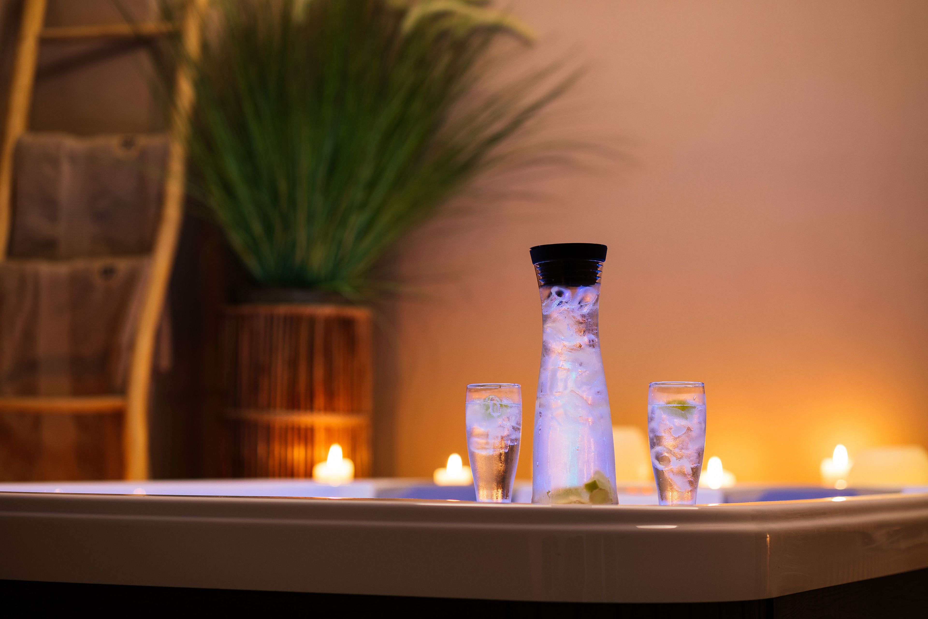 Un coin bar avec un grand verre et deux verres plus petits, qui contiennent peut-être des boissons, et des bougies en arrière-plan.